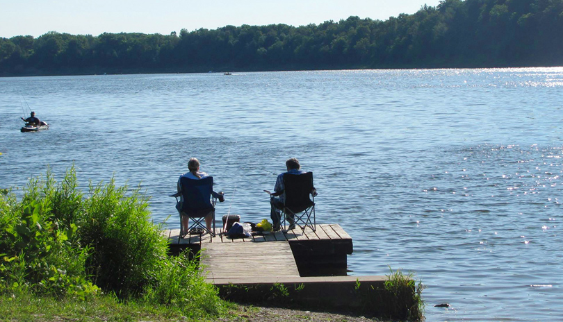 An older couple fishing on a dock at the Fanshawe Conservation Area in London, Ontario, Canada