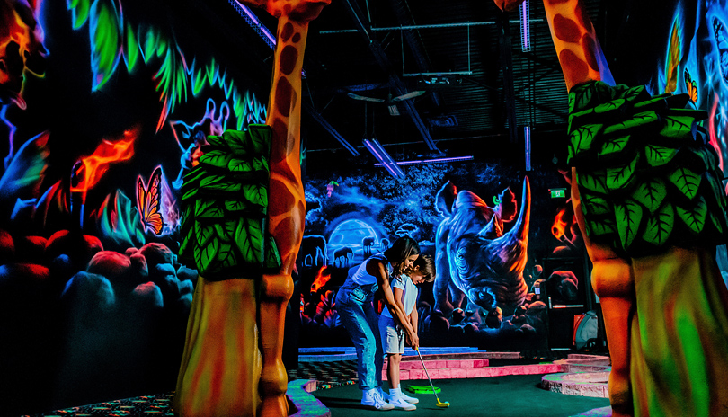 A mother and her son playing glow in the dark indoor mini golf at Fleetway in London, Ontario.