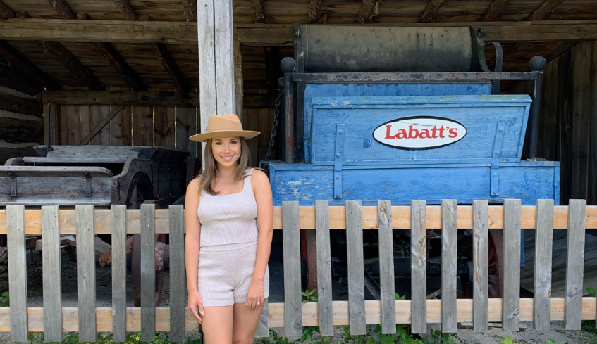 Genevieve Fisher standing in front of a historic building at Fanshawe Pioneer Village located in London, Ontario