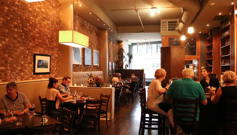 Groups of people dining and drinking in the main dining room of Gnosh Dining + Cocktails located in London, Ontario