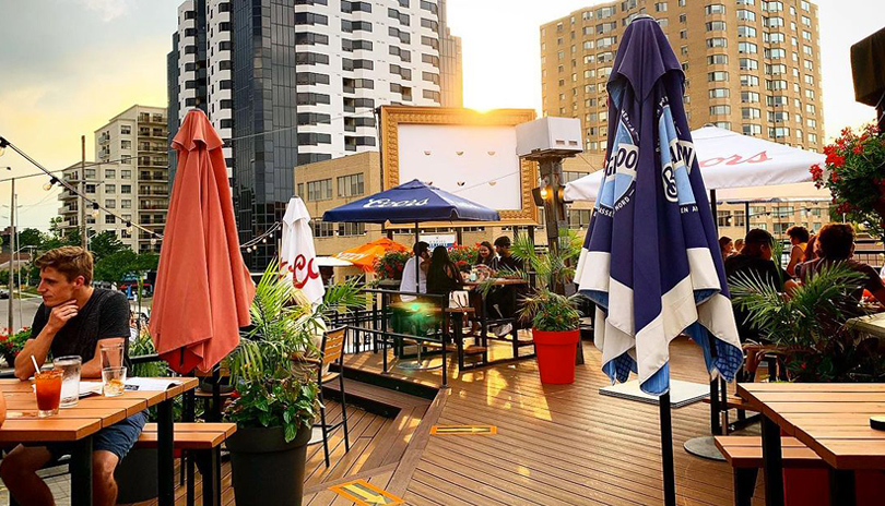 Groups of people sitting outdoors at tables in the middle of summer day at Jack Astor's Richmond Row outdoor patio located in downtown London, Ontario, Canada