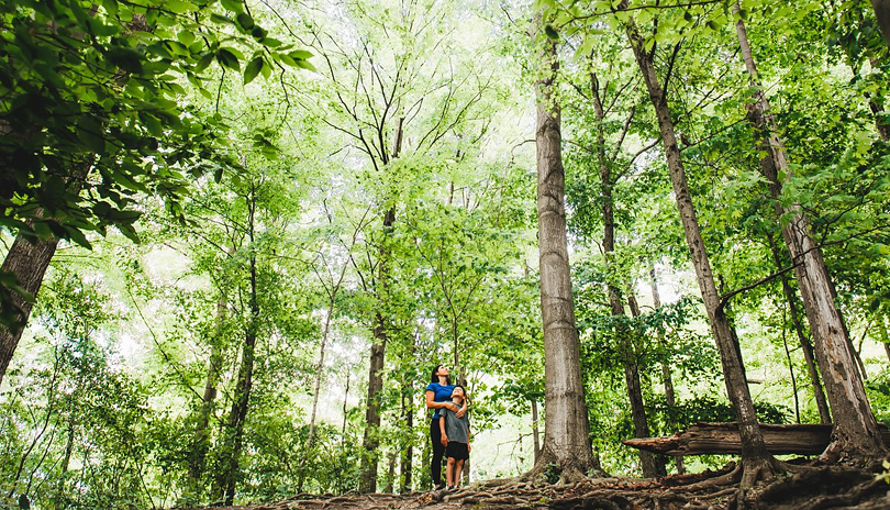 A mother and her son standing in the middle of Kains Woods looking up at very tall trees located in London, Ontario