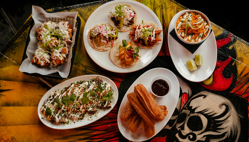 Various dishes of Mexican cuisine displayed on an illustrated table at Los Lobos located in London, Ontario