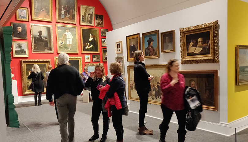 A group of people looking at various paintings on display at Museum London located in London, Ontario