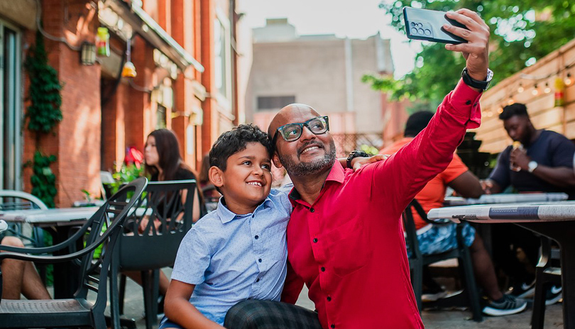 A father and his son taking a selfie together in the patio of a restaurant in London, Ontario