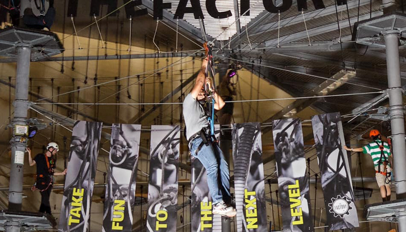 A man ziplining up high indoors at the Factory in London, Ontario