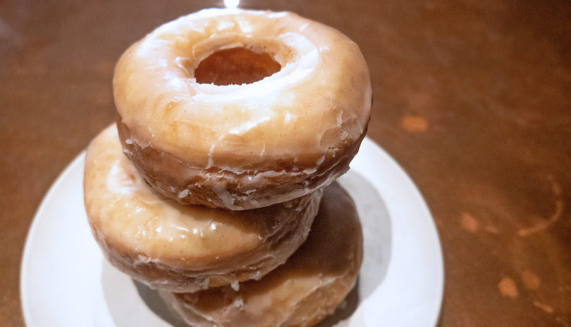 Three Vinilla glazed donuts stacked on top of each other