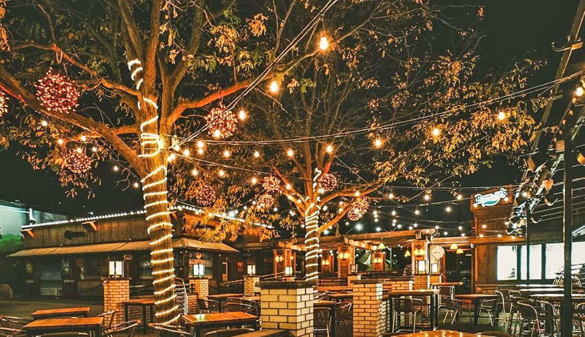 Trees with hanging lights lit up at night at the outdoor Patio of Barney’s Lounge in London, Ontario