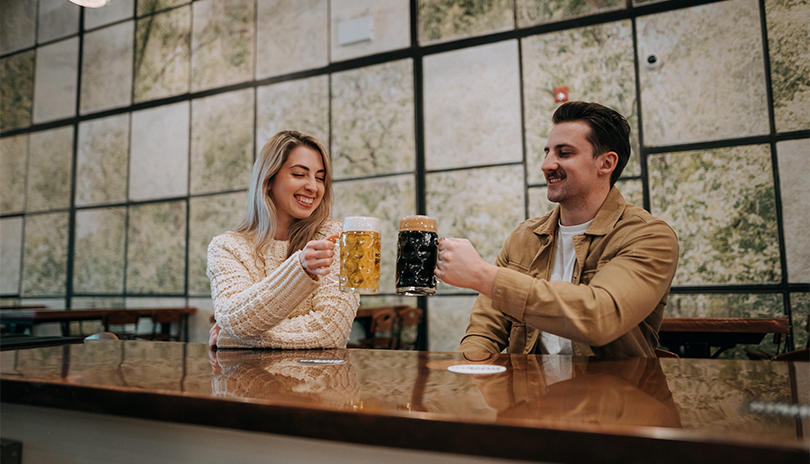 Two young people saying cheers as they enjoy a freshly poured beer at the Beer Kitchen at 100 Kellogg Lane