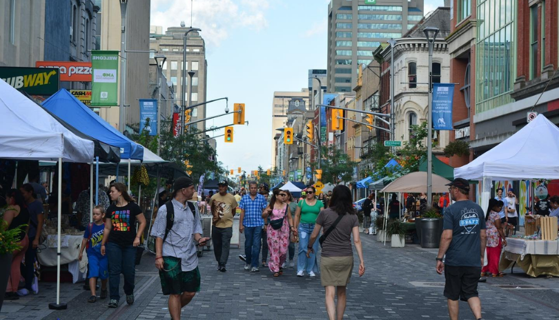 People walk on Dundas Place as an outdoor festival occurs.