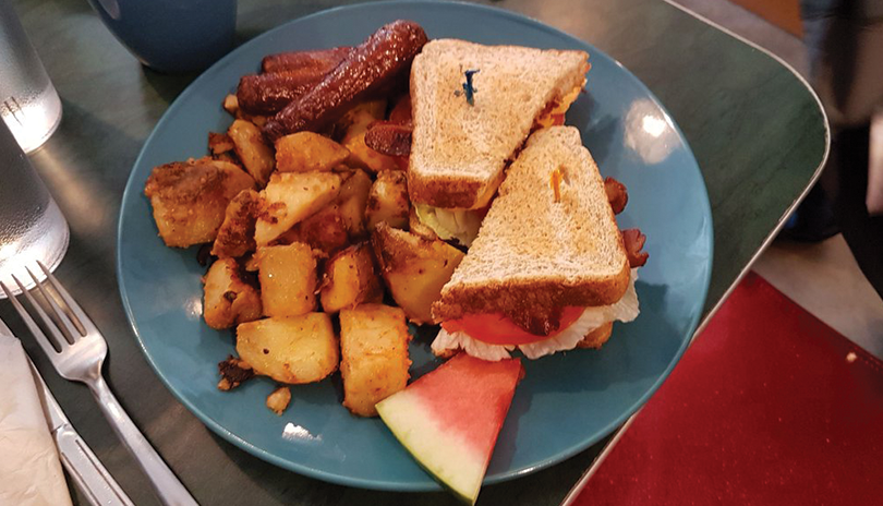 bacon lettuce and tomato sandwich toasted with sausage and home fries on a plate with watermelon