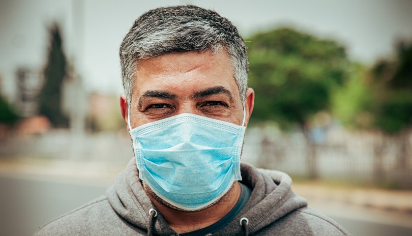 Middle-aged man wearing a non-surgical face mask looking directly into the camera