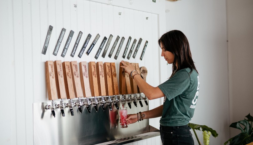 Woman pouring a glass of organic kombucha from a selection of flavours at Booch Organiz Kombucha in London, Ontario