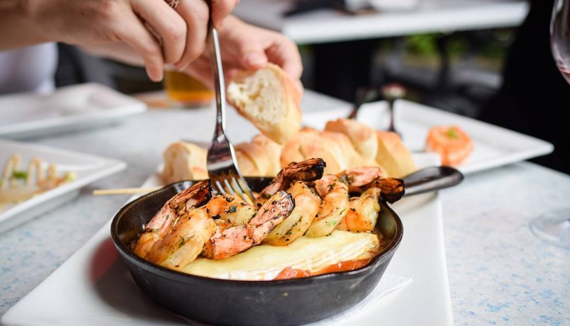 Close up of a fork diving into a freshly grilled shrimp kabob at the Church Key Bistro Pub in London, Ontario