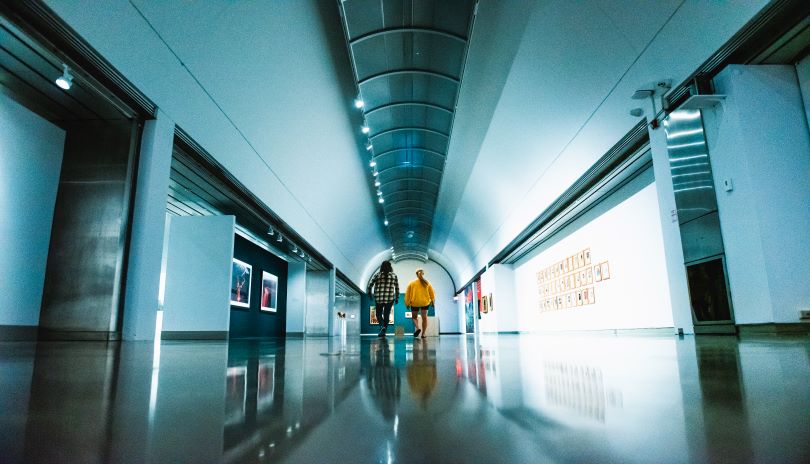 Two women walking down a coridor with various pieces of art hanging on the walls in Museum London located in London, Ontario, Canada