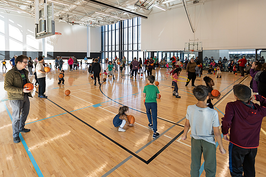 East Lions Community Centre gymnasium with a large group of children and parents playing with basketballs