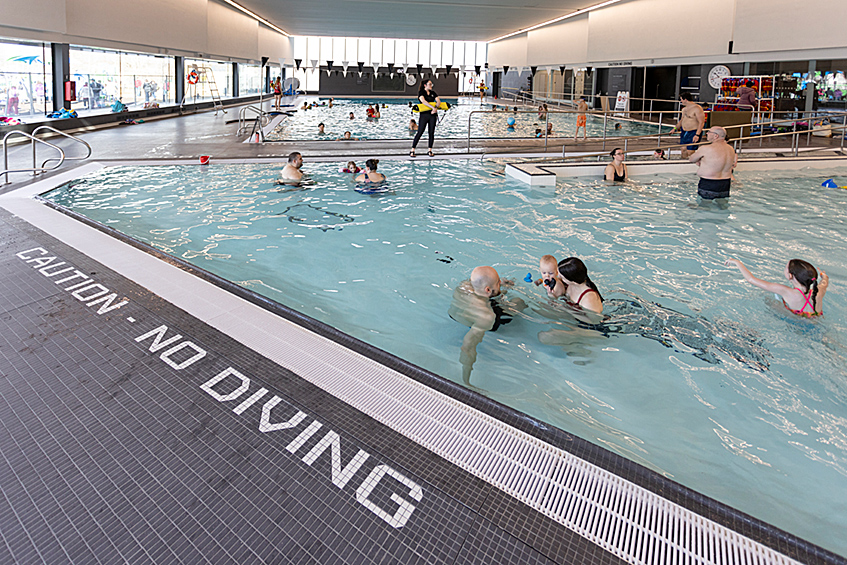 Several parents and children swimming in East Lions Community Centre pool