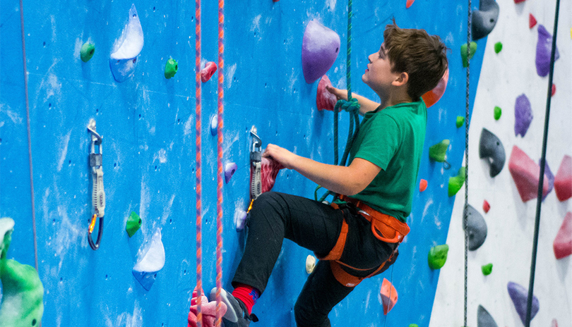 Young boy climbing a rock wall at Junction Climbing Centre in London, ON