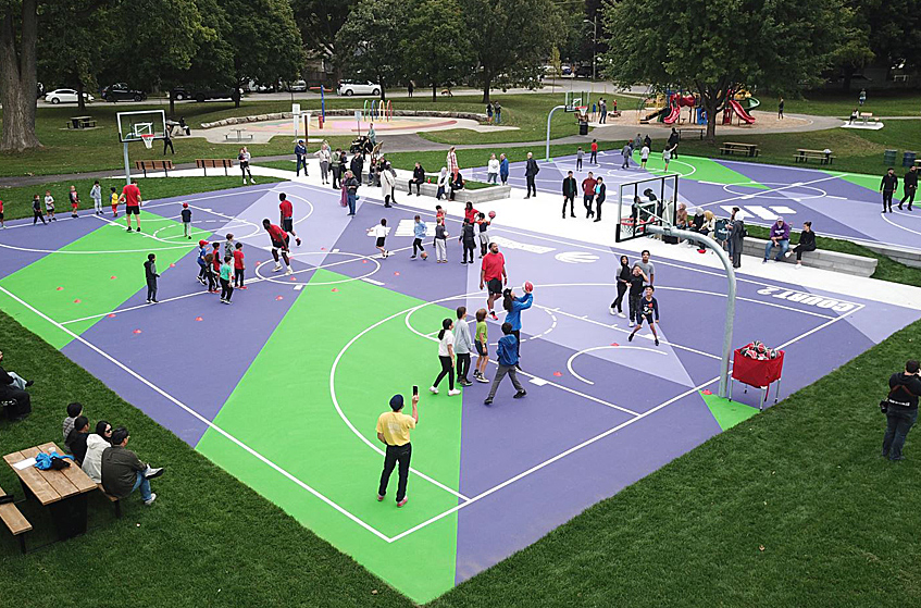 A group of people playing basketball at the Our London Family basketball courts located in London, Ontario