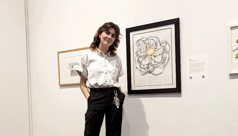 Artist MJP standing in front of a framed drawing