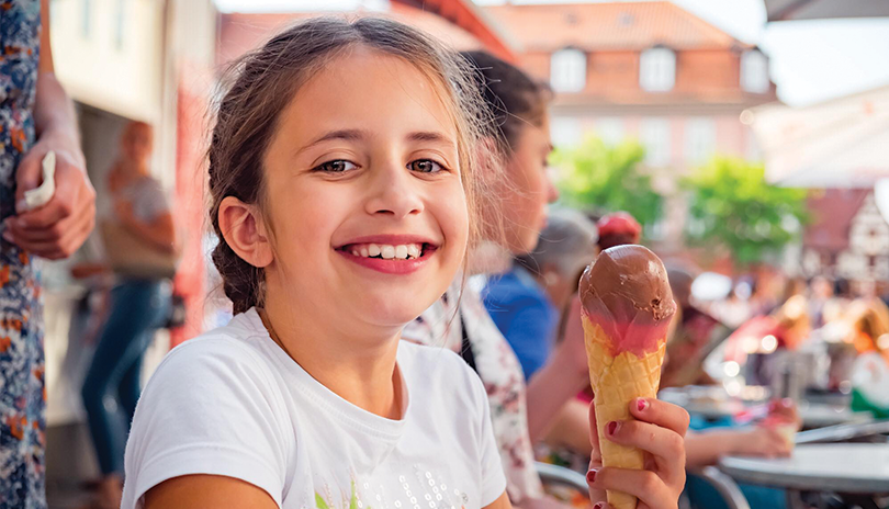 Young girl eating ice cream cone outside
