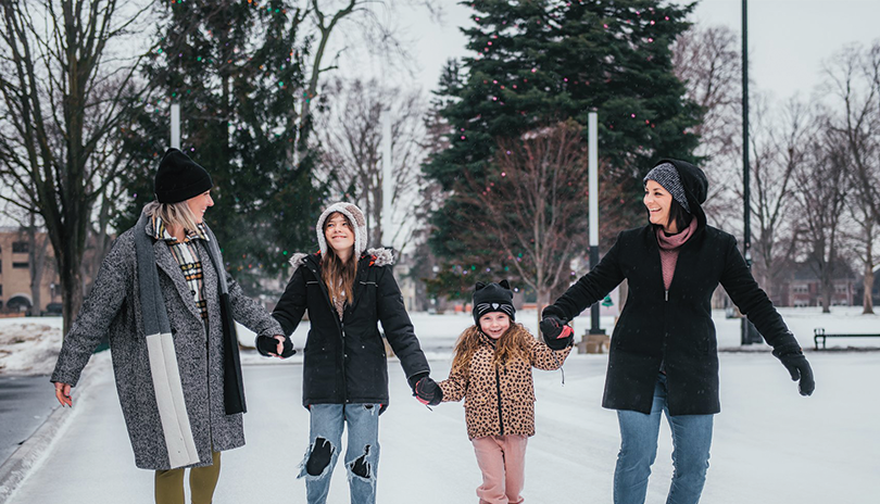 A young family laughing and enjoying skating at Victoria Park in London, Ontario