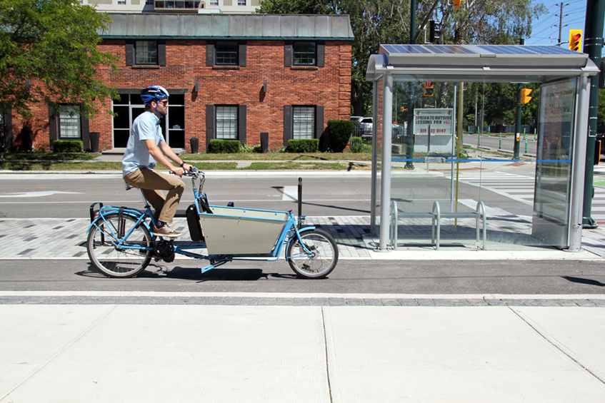 A make riding a blue bike on a bike path in downtown London, Ontario