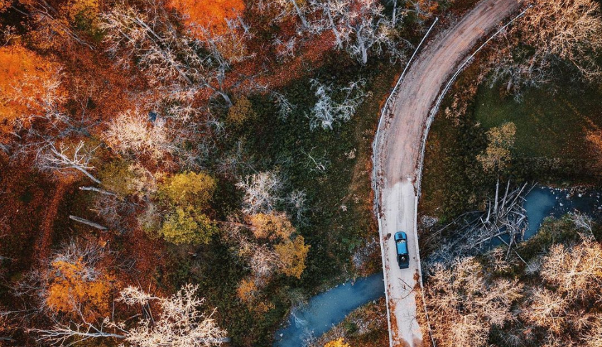 Aerial view of a car driving down a curving road with fall colours in London, Ontario