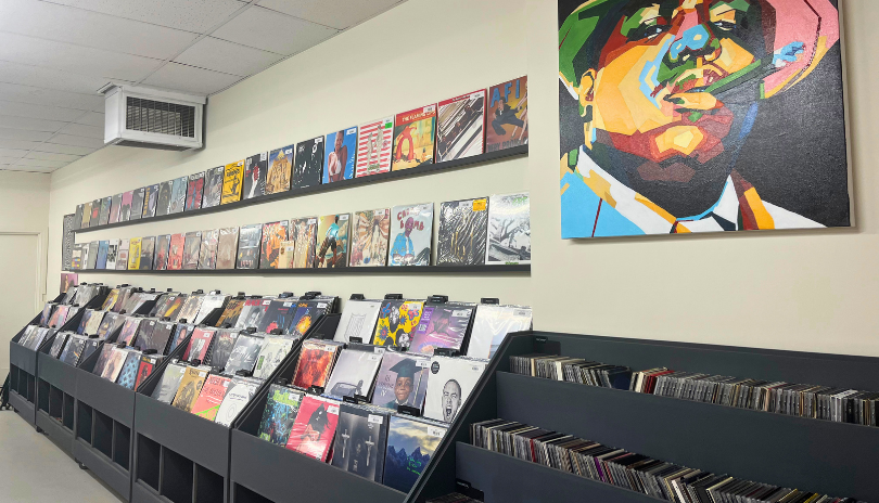 A shelf of vinyl records in a well-lit shop under a painting at Atomic Sound in London, Ontario.
