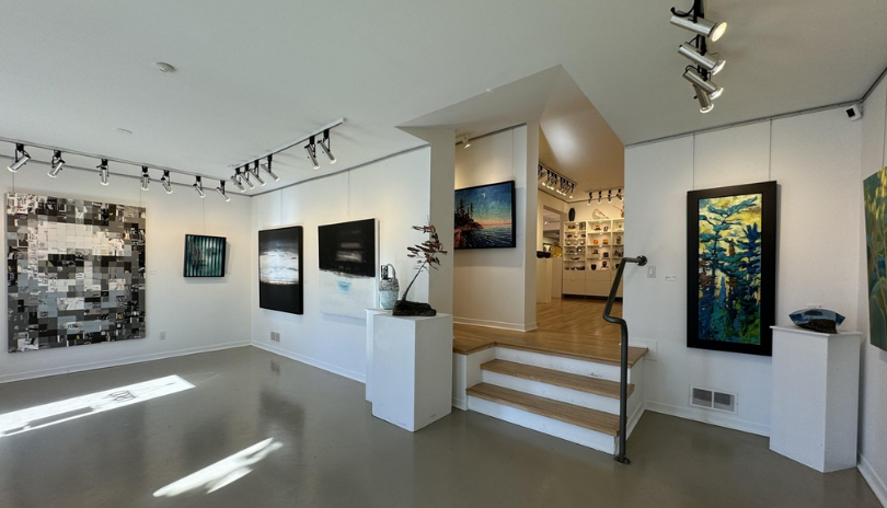 A beautifully lit art gallery with a main floor and small steps up to a second floor.