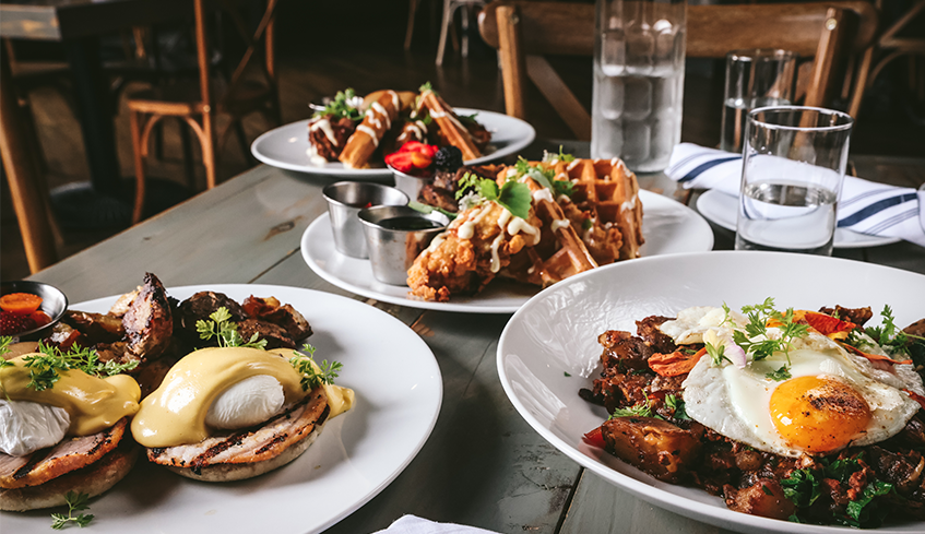 three plates of brunch inspired food on a grey wooden table