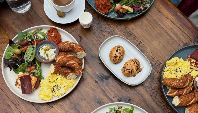 A wooden table with delicious breakfast plates set on it at The Cappa in London, Ontario.
