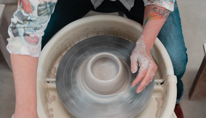 A close up of hands spinning a clay bowl on a pottery wheel at Clayworx in London, Ontario.