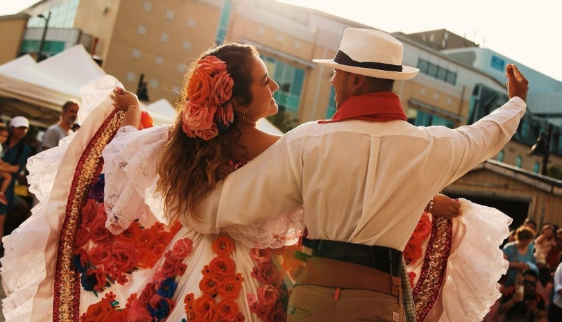 Two dancers in cultural clothing at Colombian Gastronomy Festival.