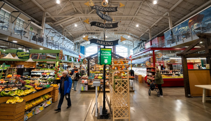 A bustling market space with fresh produce vendors and signage.