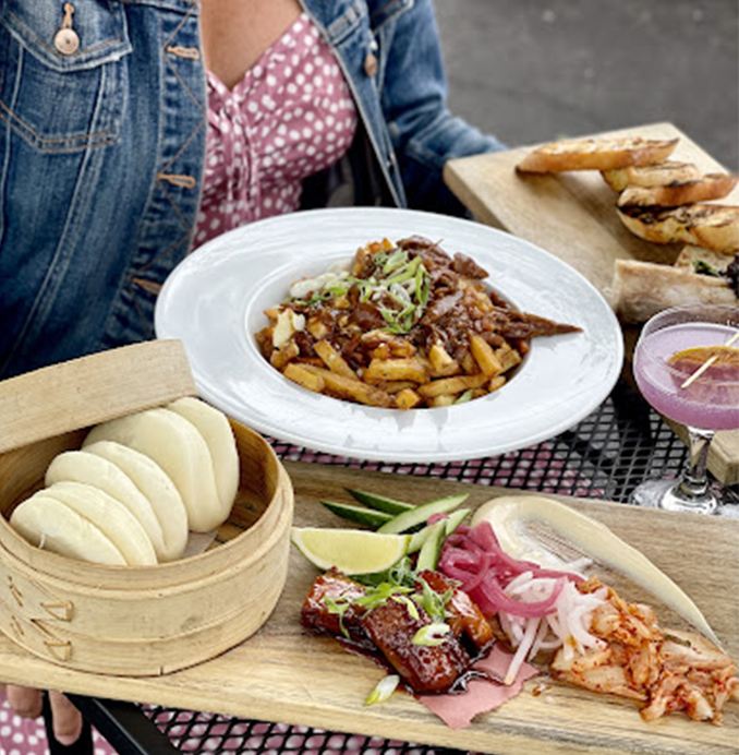 poutine and bao on a table with drinks to the side