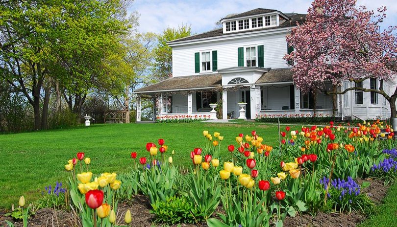 Exterior view of the Eldon House building with bright coloured flowers in the foreground located in London, Ontario