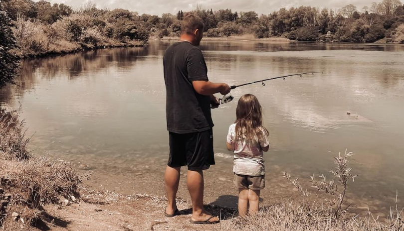 A man and a young girl fish on the shore in London, Ontario.