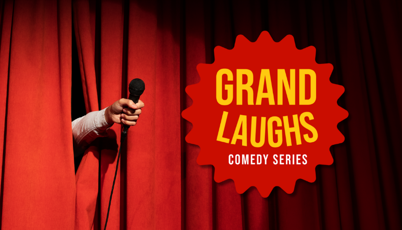 A hand sticks out of red curtains holding a microphone with a logo that says Grand Laughs,