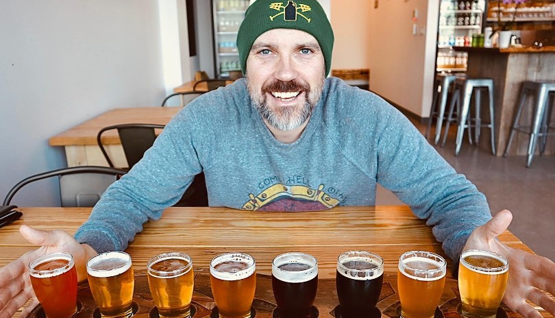 A male at a table with a sample beer flight board at Anderson Craft Ales located in London, Ontario