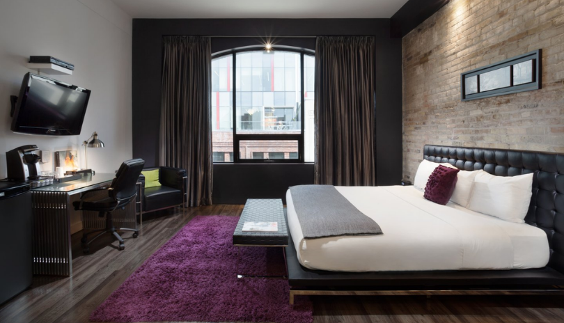 A comfortable hotel room with purple and industrial decor in downtown London, Ontario.