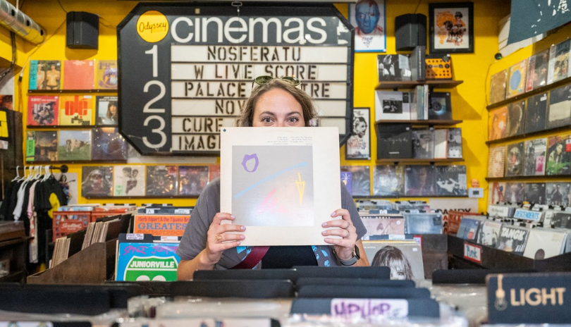 A woman holds a records in front of her face in Odyssey Records & Cinema shop in London, Ontario.