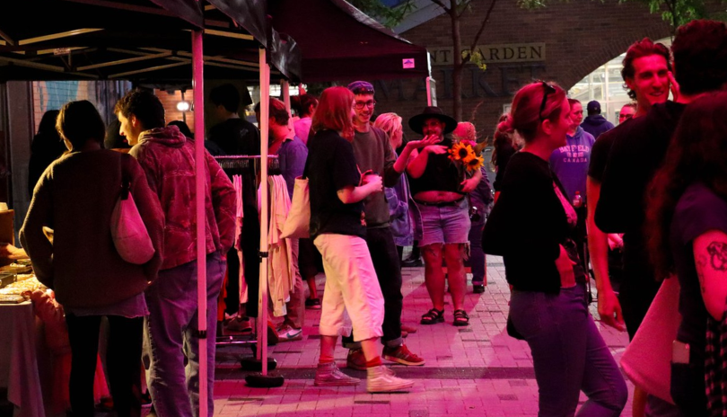 A small crowd in an alley for an outdoor market at night.