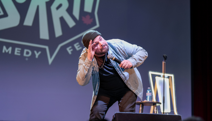 A man leans over and makes a silly face at a comedy show in London, Ontario.