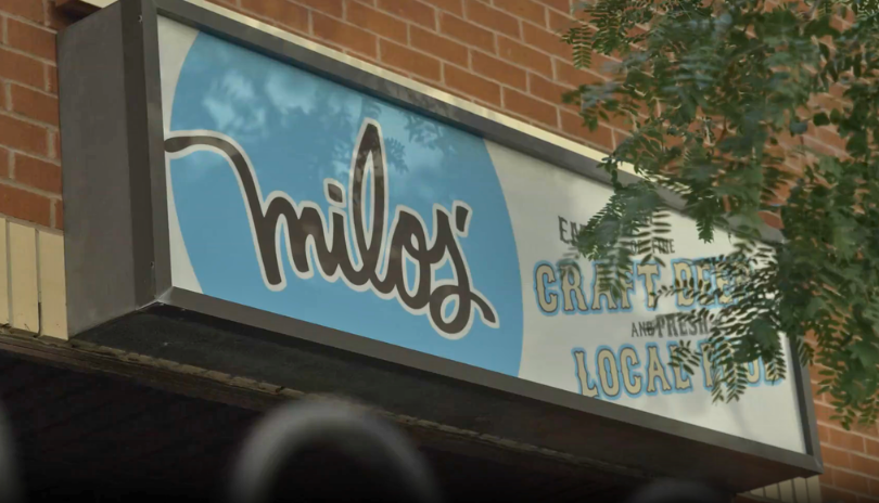 Exterior of Pub Milos with a blue sign and the business name on it.