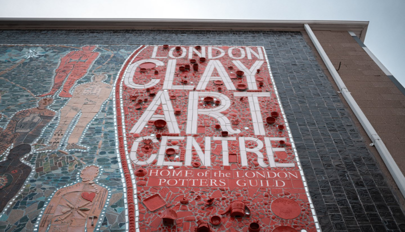 A view looking up at a large-scale ceramic mosaic that says London Clay Art Centre in London, Ontario.