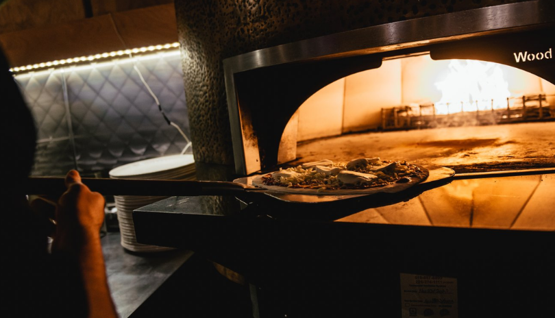 A pizza goes into a wood-fired pizza oven at Toboggan Brewing in London, Ontario.