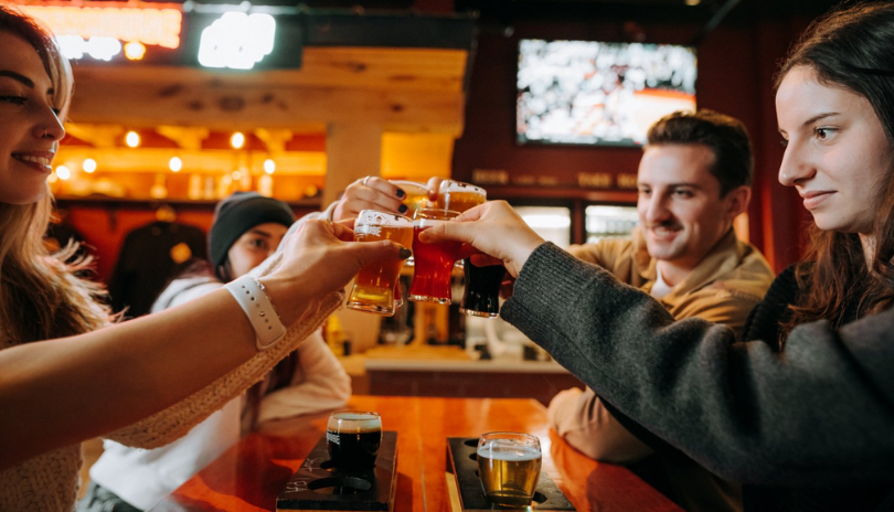 Four people cheers with glasses of beer at Powerhouse Brewing in London, Ontario.