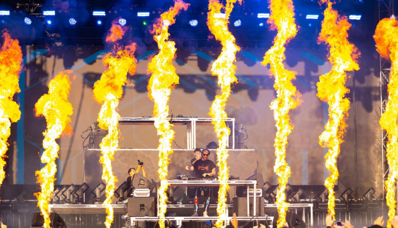 A DJ plays a set onstage surrounded by fire during Rock the Runway in London, Ontario.