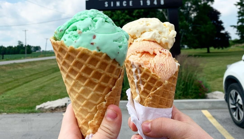 Hands hold two ice cream cones outside of Shaw's Ice Cream.